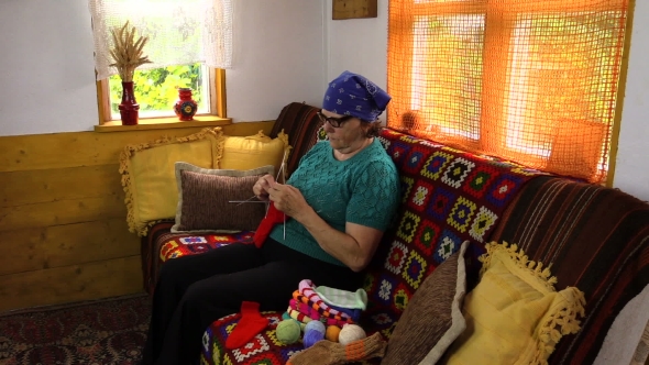 Old Senior Grandmother Woman Sit On Sofa And Knit Stockings