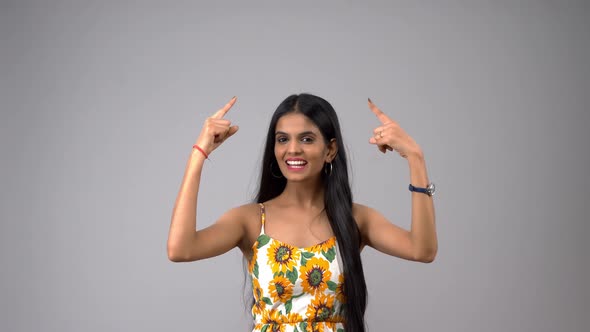 Happy and excited Indian girl pointing upwards for ad, product placement,  banner, etc alt