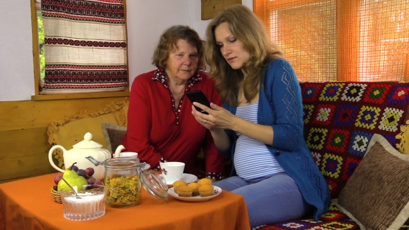 Smiling Pregnant Granddaughter Show Mobile Phone To Grandmother