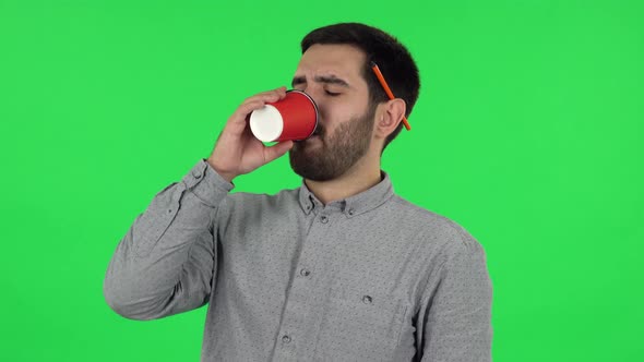 Portrait of Brunette Guy Drinking Unpalatable Coffee and Is Disgusted. Green Screen alt