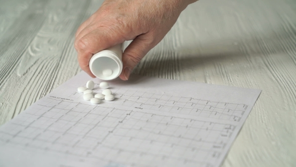 Hand Pours Out Pills From The Bottle On The Table alt