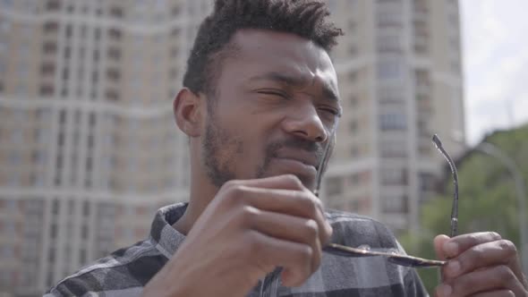 Close Up Face of Confidient African American Man Standing Against the Background of Urban Building alt
