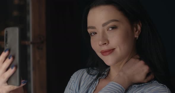 The Girl Is Taking a Selfie and Looking To the Camera.  alt