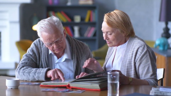 Elderly Happy Couple Looking Old Photo Album And Smiling, Stock Footage