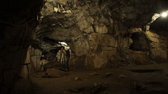 A Young Woman Is Standing Inside a Rock Cave alt