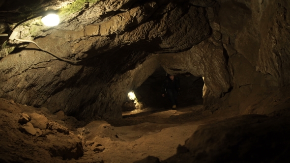 A Young Man Is Standing Inside a Rock Cave alt