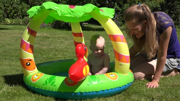 Mother Care Baby Daughter First Time In Small Child Pool With Water.