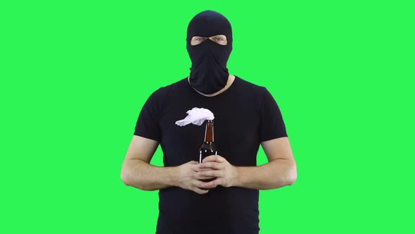 A man in a black mask holds in his hand a bottle of Molotov cocktail
