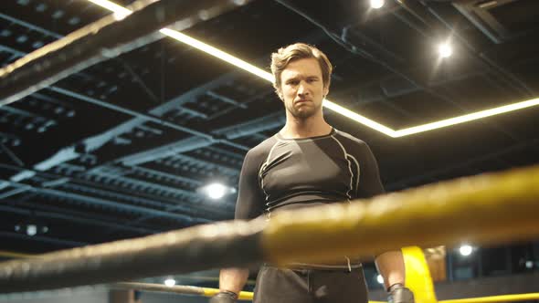 Annoyed Fit Man Hitting Fists on Boxing Ring. Sport Man Getting Ready for Fight alt