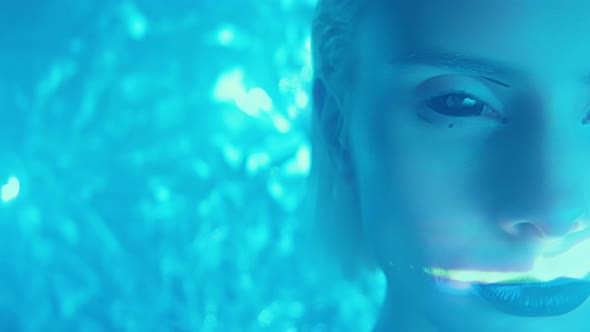 Woman with Black Eyes and Lips in Neon Light and Laser Beams alt