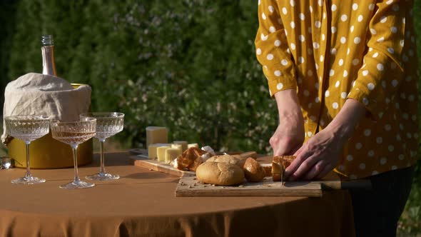 Female in polka dot shirt cut bread for snacks for outdoor party