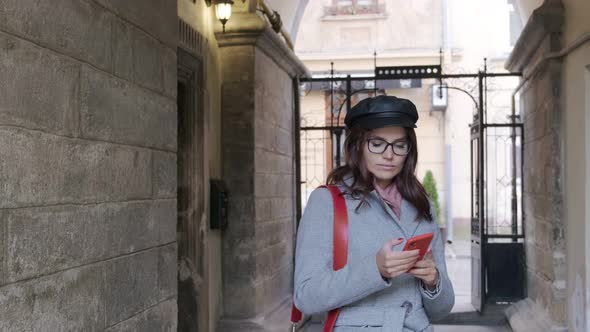 Young Beautiful  Girl In Autumn Dress Uses A Smartphone.