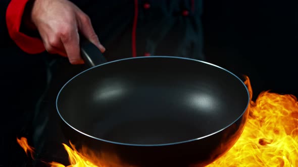 Super Slow Motion Shot of Chef Holding Empty Frying Pan and Flames at 1000Fps. alt