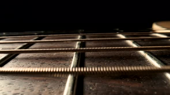 Slider Macro Shot of an Acoustic Guitar Neck with Metal Strings and Frets on Black Background alt