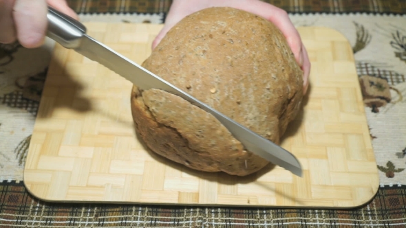 Rye-wheat Bread Is Cut With a Knife On a Board