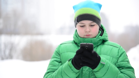 Boy Uses a Cell Phone With Gloves Outside In Winter