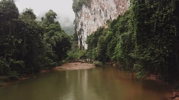 Moving Above the River Between Jungle Trees to the Mountains