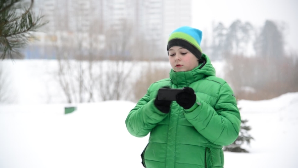 Boy Uses a Cell Phone With Gloves Outside In Winter