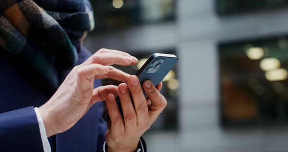 A Man Uses a Mobile Phone Standing in Business Center of the City alt
