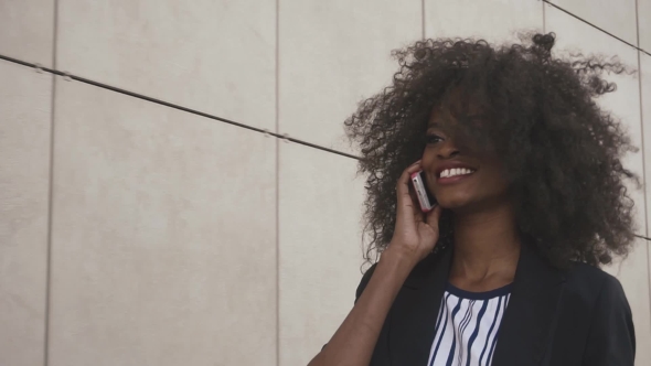 Attractive African American Business Lady Talks By Phone On The White Textured Wall Background