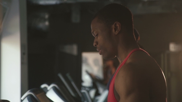 Side View of Muscular Handsome Black Man Jogging on a Treadmill in the Gym