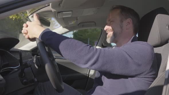 A Middleaged Handsome Caucasian Man Acts Happy As He Sits in His Car  Side Closeup