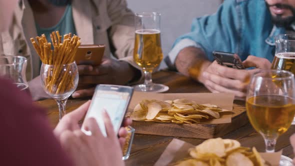 People sitting together in bar and using their smartphones