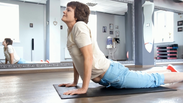 Senior Woman Stretching Out In Fitness Room, Yoga Exercise