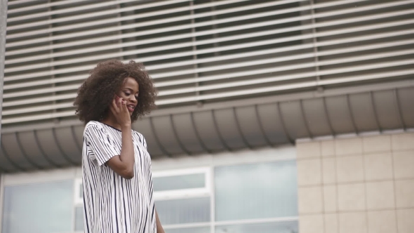 Gorgeous African American Woman Talks By Phone On The Massive Airport Wall Background