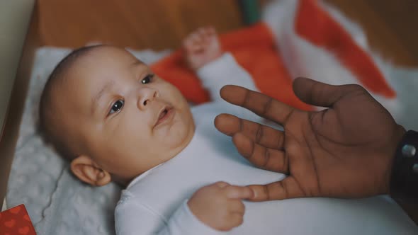 Adorable African American Black Baby Playing with Fathers Hand While Lying on the Blanket Surrounded alt