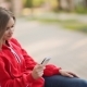 Young Woman Sitting On a Bench In The Park With White Phone - VideoHive Item for Sale