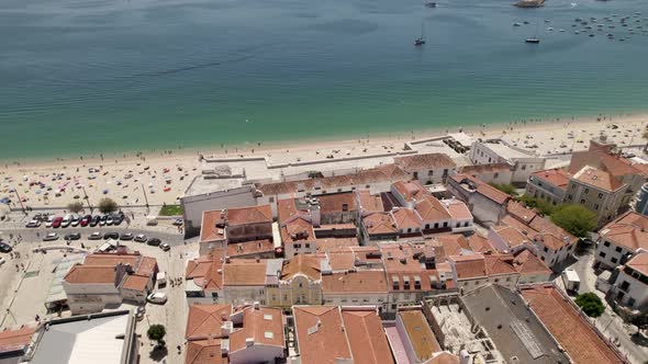 Aerial backwards of a wonderful beach and the village behind. Sesimbra, Portugal. Real time alt