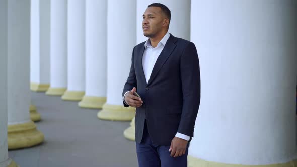 Portrait of Handsome Thoughtful African American Man in Formal Business Suit Standing at White alt