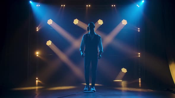 Silhouette a Young Stylish Guy Vocalist Singing and Gestures with His Hands on Stage in a Vintage alt