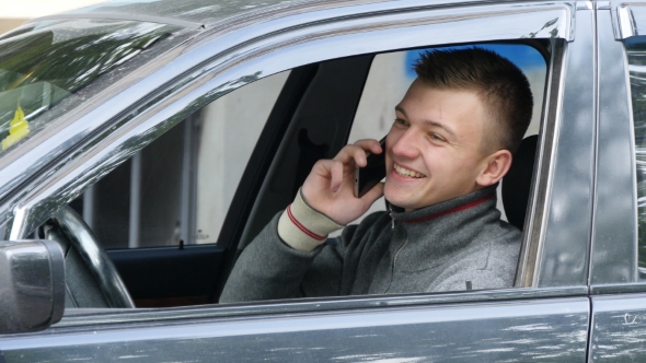 Happy young man speaking on the phone in the car alt