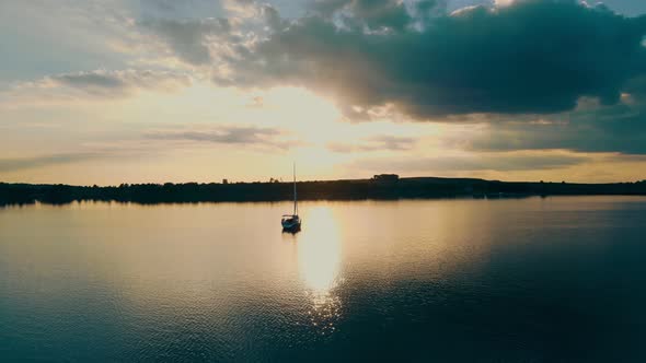 Aerial View One Yacht at Sunset Near the Barge. Flight at Sunset Near the Yacht with a Sail. The Sun alt