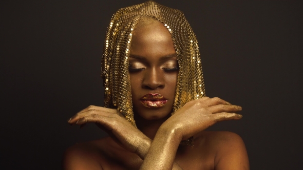 Surreal Fashion Portrait Of African American Female Model With Golden Glossy Headwear