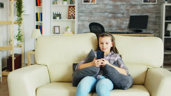 Cheerful Little Girl with Braces Sitting on the Couch alt