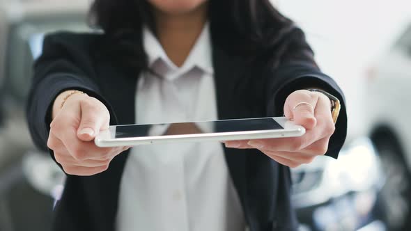 Image for Graphic Implements. Closeup of a Girl in a Business Suit Holds a Tablet Outstretched Hands