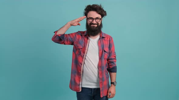 Happy Bearded Guy Saluting with Hand, Saying Yes Sir, on Turquoise Background alt