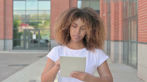 African Woman Browsing Internet on Tablet While Walking Outside alt