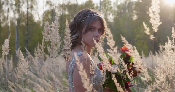 A Young Woman Dressed in a Gray Wedding Dress. She Has Flowers in Her Hand and Is in the Park. alt