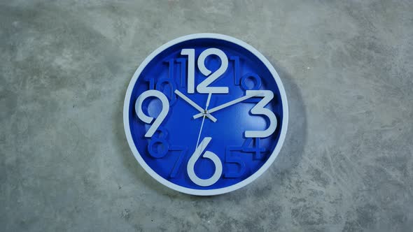 A Blue Office Clock Hangs on a Gray Concrete Wall by magicstock | VideoHive