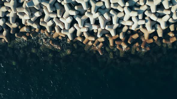 Top down view of concrete blocks in the water, drone moving backward, abstract natural pattern