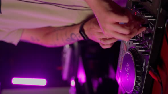 DJ using console in club close up. Male person touching twist buttons on control device by hands alt
