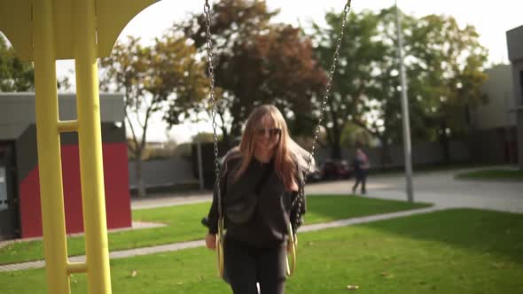 Long Haired Woman Swinging on a Swing in the Green Park Happily Smiling alt