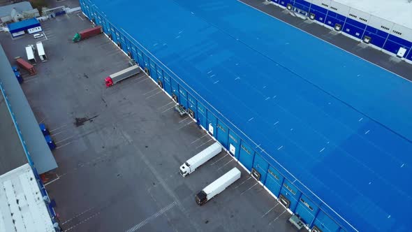 Aerial Top View of the Large Logistics Park with Warehouse with Some Semi-trailers Trucks. alt