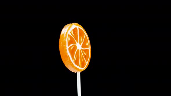 Orange Lollipop Multicolor On A Black Background Is Spinning. alt