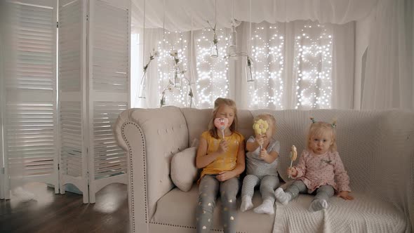 Three Sisters Girl Sitting on Comfort Sofa and Eating Candy on s alt