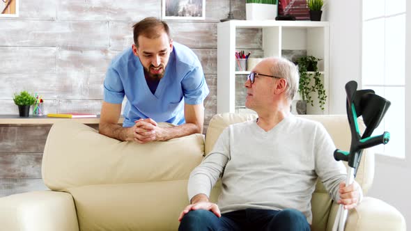 Elderly Man Having a Conversation with a Male Nurse in Cozy Nursing Home alt